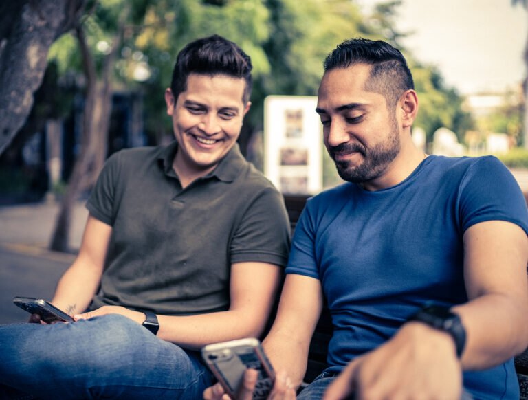 Young gay couple using mobile phones outdoors